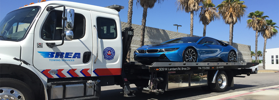 Brea Towing flatbed truck carrying a BMW