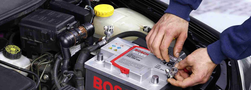 Battery service technician replacing car battery